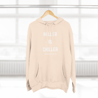 The Miller is Chiller - Miller Beach Three-Panel Fleece Hoodie from Printify features bold white text reading "MILLER IS CHILLER" on the front, with smaller text below stating "MILLER BEACH - GARY, IN." This comfortable black hoodie includes a front pocket and drawstrings.