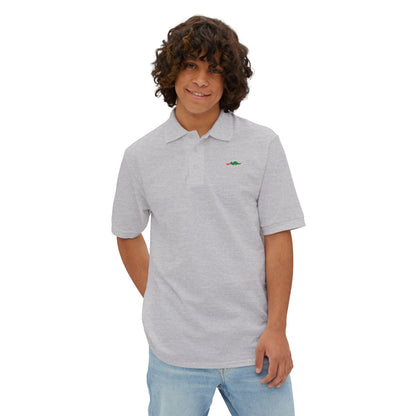 A person with curly hair wearing a navy blue Printify Braggin' Dragon - 1980s Sears Men's Piqué Polo, featuring a small embroidered dragon logo on the left chest, smiles against a plain white background.