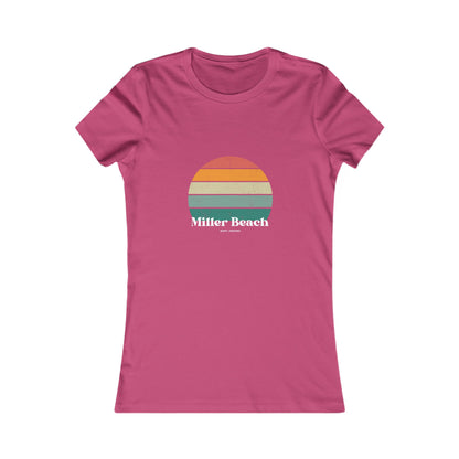 The Printify Women's Favorite Tee - Miller Beach Gary, IN Retro Sunset is a pink women's T-shirt showcasing a retro-style graphic of a sun with horizontal stripes in orange, yellow, and green. Designed with a feminine fit, the airlume combed cotton fabric offers premium softness. Below the sun, the text reads "Miller Beach" in white, with smaller text underneath that is not legible.