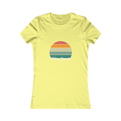 The Printify Women's Favorite Tee - Miller Beach Gary, IN Retro Sunset is a pink women's T-shirt showcasing a retro-style graphic of a sun with horizontal stripes in orange, yellow, and green. Designed with a feminine fit, the airlume combed cotton fabric offers premium softness. Below the sun, the text reads "Miller Beach" in white, with smaller text underneath that is not legible.