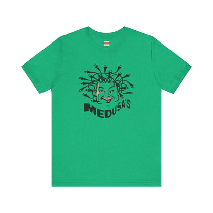 A cream-colored unisex jersey short sleeve tee from Printify, titled "Medusa's 1980s Dance Club Chicago," features a black and white illustration of a cartoonish Medusa head. The soft cotton design showcases numerous snakes as hair with a smiling face. Below, the word "MEDUSA'S" is printed in bold, playful font.