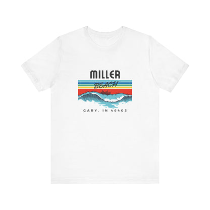 The Miller Beach 46403 Surf Style - Unisex Jersey Short Sleeve Tee by Printify features a retro surf-inspired design on a yellow background. The shirt displays "MILLER BEACH" above waves with a skyline illustration, while "Cary, IN 46403" is printed below the waves. The vibrant design also includes colorful stripes in shades of blue, red, and orange.