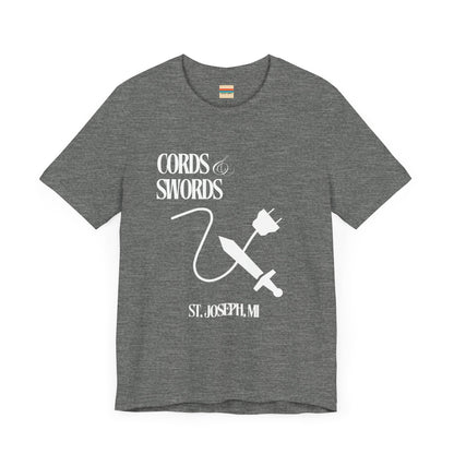 The SoCool Podcast - Cords & Swords Store T-Shirt by Printify is a vintage-inspired blue shirt that showcases a white graphic with the text "Cords & Swords" above illustrations of a crossed power cord and sword, along with "St. Joseph, MI" beneath. Ideal for tech enthusiasts, this design is centered on the front against a plain white background.