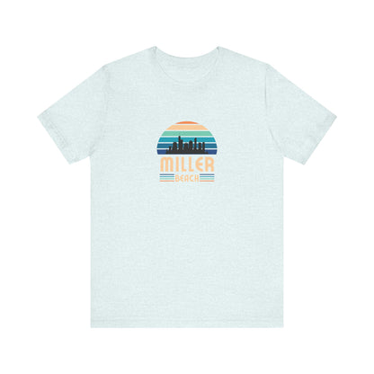 A brown unisex jersey short sleeve tee called "Miller Beach Chicago Skyline" from Printify features a vintage-style design with a sunset, the Chicago skyline, and "Miller Beach" in bold letters. The design incorporates shades of blue, orange, and yellow and is displayed against a plain white background.