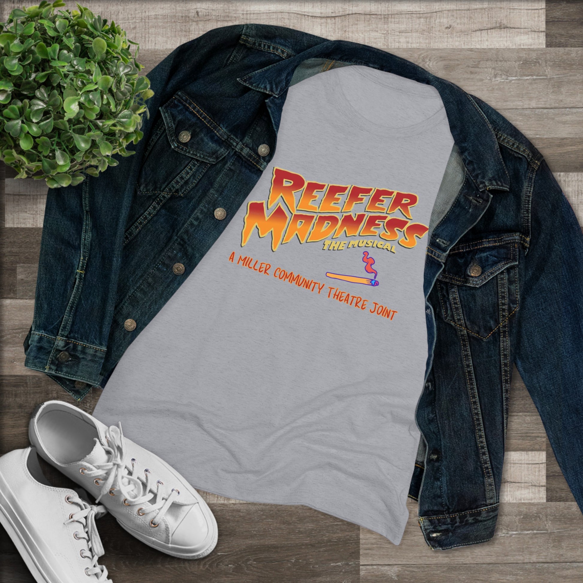 This limited-edition dark gray "Reefer Madness Cast Shirt - Miller Community Theatre - Women's Triblend Tee" by Printify features the text "Reefer Madness: The Musical" in bold, fiery letters across the chest. Below, in smaller orange text, it reads, "A Hill's Community Theatre Joint.