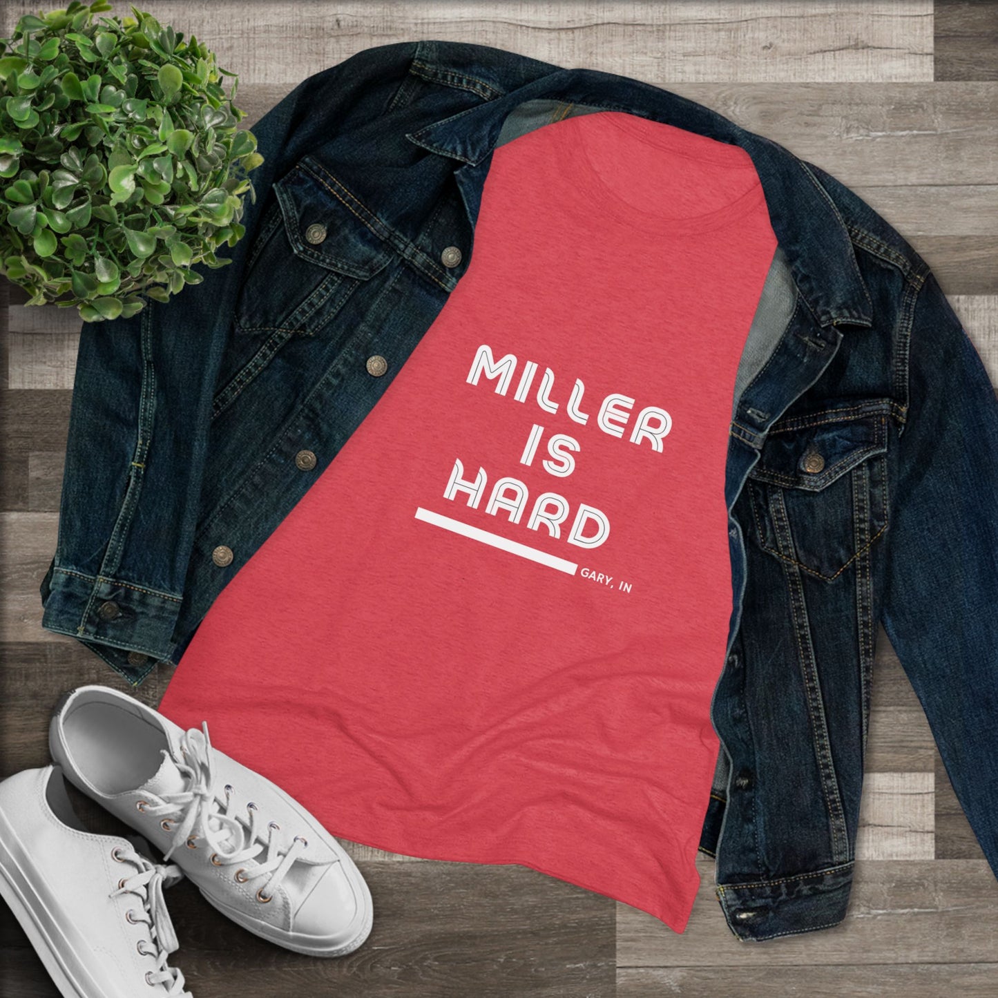 The Miller is Hard - Miller Beach Women's Triblend Tee by Printify features unique red coloring with white text that reads "MILLER IS HARD" and "GARY, IN" below, showcasing distinctive lettering spacing and alignment. Made from ultra-soft fabric, this shirt ensures a comfortable fit with a simple, casual design.