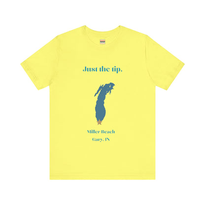 The Just the Tip - Miller Beach Unisex Jersey Short Sleeve Tee by Printify in yellow showcases text and a graphic design. The top displays "Just the tip" above a blue silhouette reminiscent of Indiana. At the bottom, it reads "Miller Beach" and "Gary, IN." Made from soft Airlume combed cotton, this tee offers both comfort and style.