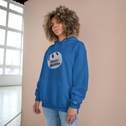 A navy blue Printify Miller Beach Wiffle Ball OG Logo - Sweatshirt, featuring a white wiffle ball graphic on the chest with "Miller Wiffle" in blue beneath it. Made from recycled polyester, this hoodie includes a front pocket, drawstrings, and the Champion logo on the left sleeve. It also offers Double Dry® technology for added comfort.