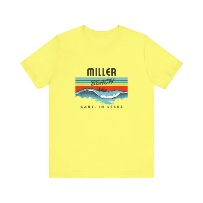 The Miller Beach 46403 Surf Style - Unisex Jersey Short Sleeve Tee by Printify features a retro surf-inspired design on a yellow background. The shirt displays "MILLER BEACH" above waves with a skyline illustration, while "Cary, IN 46403" is printed below the waves. The vibrant design also includes colorful stripes in shades of blue, red, and orange.