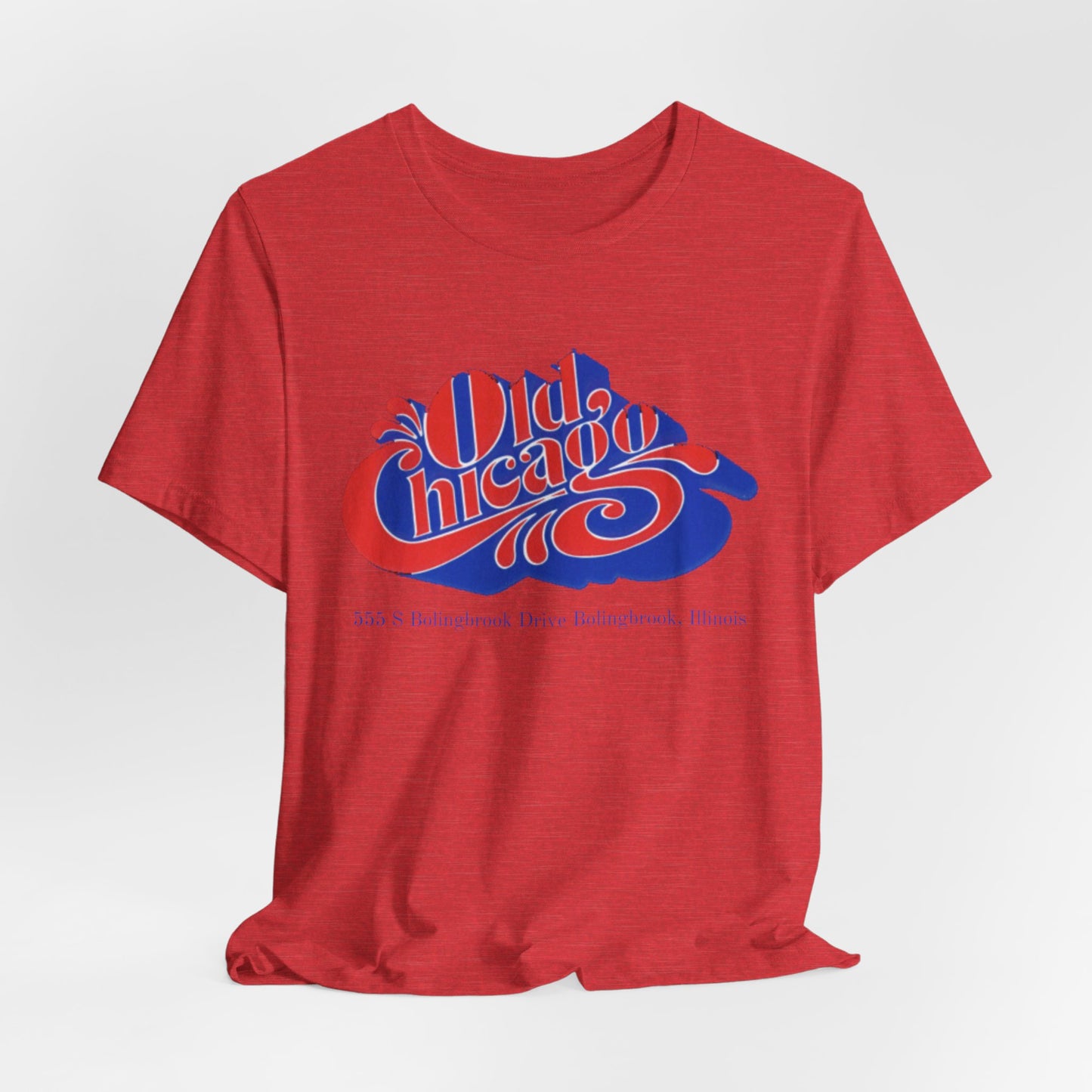 The "Old Chicago Mall Bolingbrook 1980s Retro - Unisex Jersey Short Sleeve Tee" from Printify is a gray T-shirt showcasing a vintage design with the text "Old Chicago" in blue and red. Beneath the main text, the address "355 S. Bolingbrook Drive, Bolingbrook, Illinois" appears in smaller font, evoking 80s nostalgia of the Old Chicago Mall. The shirt is displayed against a white background.