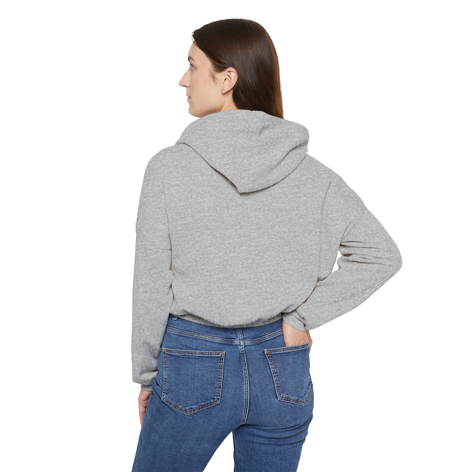 A person confidently stands in front of the camera with one hand on their hip, wearing a Printify "Say Perhaps to Drugs" Women's Cinched Bottom Hoodie. Crafted from soft Airlume cotton, this light-colored cropped hoodie pairs stylishly with blue jeans.