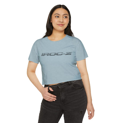 A grey, short-sleeve, rounded-neckline Women's Festival Crop Top by Printify, featuring "IROC-Z" printed in bold black letters across the chest. Perfect for any festival, this Chevrolet Iroc Z-inspired top from the 1980s stands out against a plain white background.