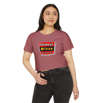 The Shakey's Pizza - Women's Festival Crop Top from Printify is a light blue garment that proudly displays the iconic Shakey's Pizza logo on the chest. Featuring retro-style red and black signage with text in white, yellow, and red that reads "Shakey's Pizza Restaurant," this crop top exudes a vintage-inspired charm.