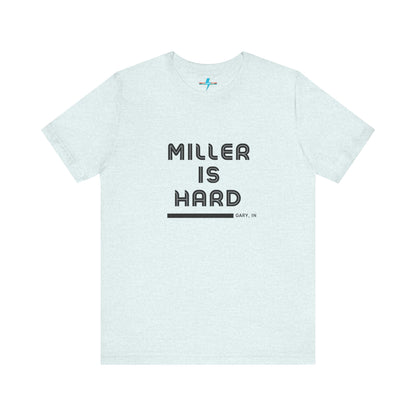 A unisex jersey short sleeve tee from Printify in burnt orange features the bold black text "MILLER IS HARD" on the chest, with "GARY, IN" written beneath in smaller black font. Perfect for showcasing Miller Beach's iconic spirit, this t-shirt is displayed against a plain white background.