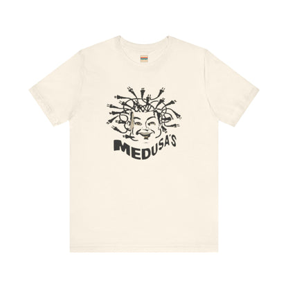 A cream-colored unisex jersey short sleeve tee from Printify, titled "Medusa's 1980s Dance Club Chicago," features a black and white illustration of a cartoonish Medusa head. The soft cotton design showcases numerous snakes as hair with a smiling face. Below, the word "MEDUSA'S" is printed in bold, playful font.