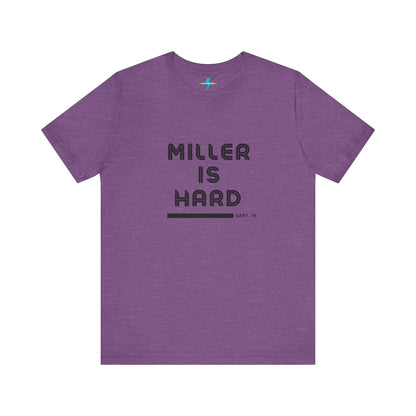 A unisex jersey short sleeve tee from Printify in burnt orange features the bold black text "MILLER IS HARD" on the chest, with "GARY, IN" written beneath in smaller black font. Perfect for showcasing Miller Beach's iconic spirit, this t-shirt is displayed against a plain white background.