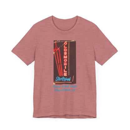 The Blue Island Illinois Steele-Hopf Oldsmobile Unisex Jersey Short Sleeve Tee by Printify features a vibrant red design with an image of a vintage neon sign. The sign displays "OLDSMOBILE" in vertical red letters and "Strafford" in blue cursive script. Below the sign, light blue text reads "Sleets Hopf Olds" and "Blue Island, IL," making it an ideal retro-inspired tee for classic car enthusiasts.