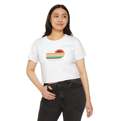 The Miller Beach Gary, IN Gradient Sunset - Women's Festival Crop Top by Printify is a mauve-colored T-shirt showcasing a retro-style graphic design of a sunset with multicolored stripes and a city skyline silhouette. Ideal for festival season, the text below reads "Miller Beach Gary, IN." Crafted to be soft and durable, this custom crop top provides both comfort and style throughout the day.