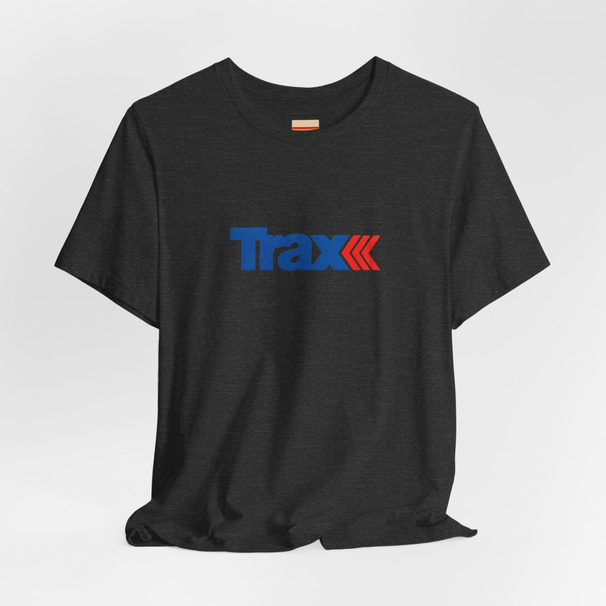 A gray unisex jersey short sleeve tee from Printify, inspired by retro 1980s Kmart style. The "Trax" logo is printed in blue letters, followed by three red arrows pointing to the right. This classic Trax Brand T-shirt is laid flat against a white background, capturing nostalgic fashion vibes.