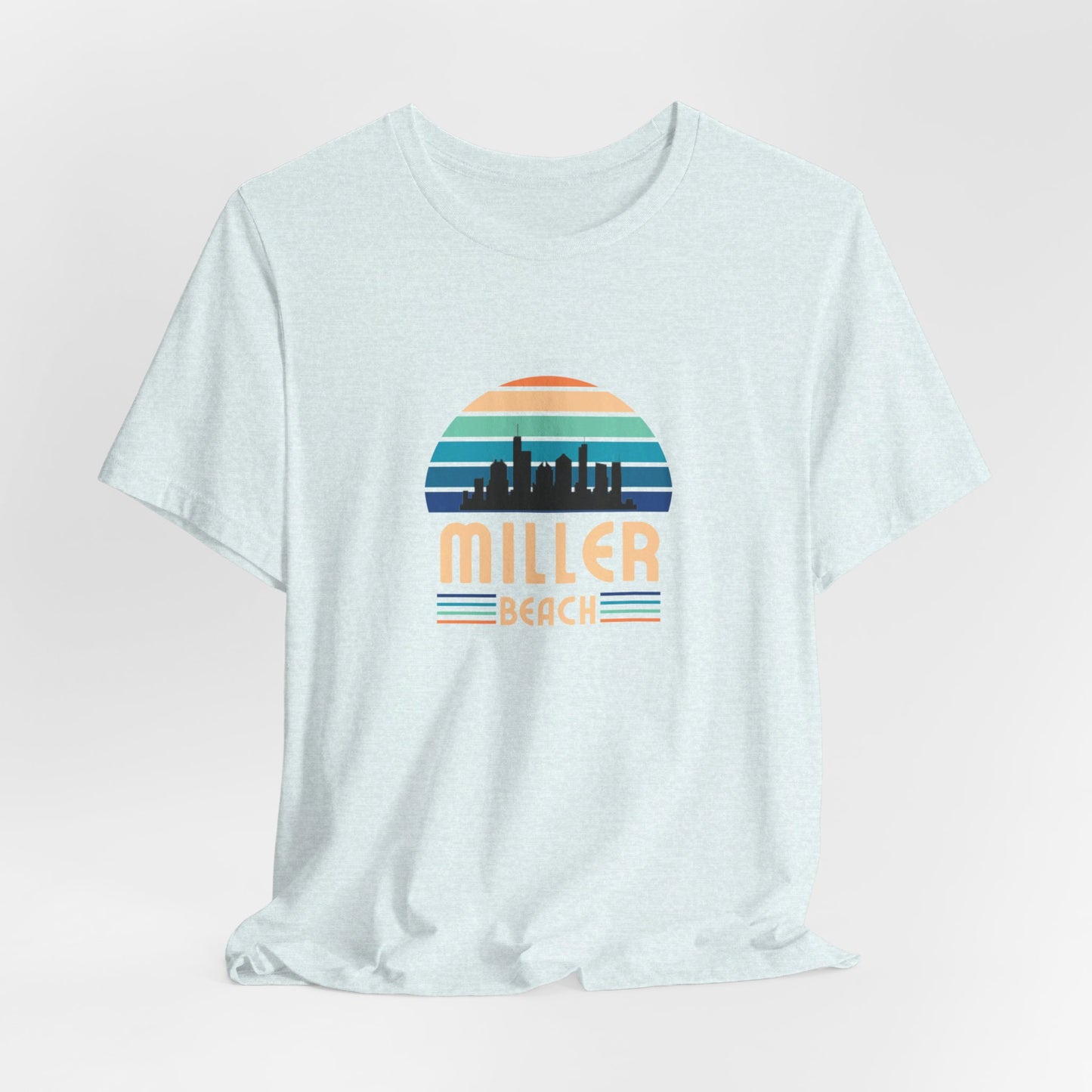 The Printify Miller Beach Chicago Skyline - Unisex Jersey Short Sleeve Tee is a light blue T-shirt featuring a stylized graphic of the Chicago skyline against a setting sun with gradient shades of blue and orange. Below the graphic, "Miller Beach" is printed in bold, yellow letters.