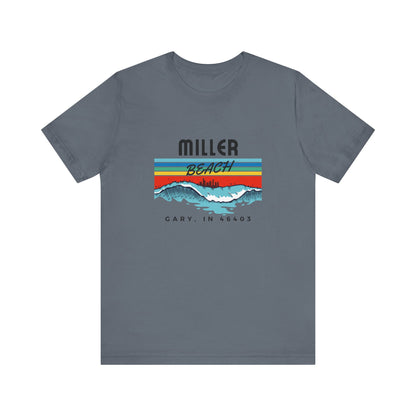 The Miller Beach 46403 Surf Style - Unisex Jersey Short Sleeve Tee by Printify features a retro surf-inspired design on a yellow background. The shirt displays "MILLER BEACH" above waves with a skyline illustration, while "Cary, IN 46403" is printed below the waves. The vibrant design also includes colorful stripes in shades of blue, red, and orange.