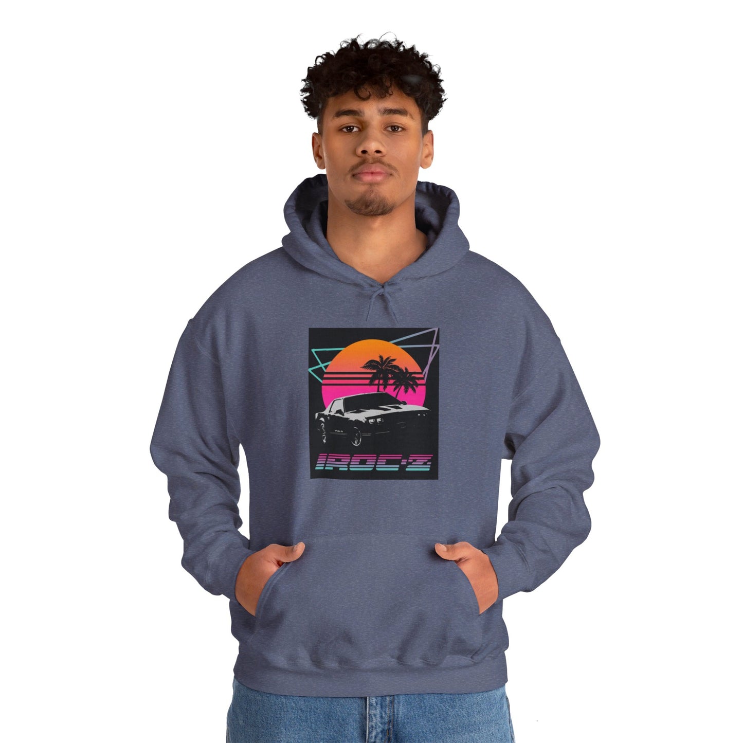 Introducing the Chevrolet IRoc Z28 - 1980s Retro Hoodie by Printify: This vibrant pink hoodie showcases a striking retro design on the front, featuring a classic American muscle car set against an orange and red sunset with palm trees, intersected by geometric shapes. The text "IROCZ" is prominently displayed below the image. Offering a relaxed fit and equipped with a front pocket, this hoodie perfectly captures the essence of 1980s style.