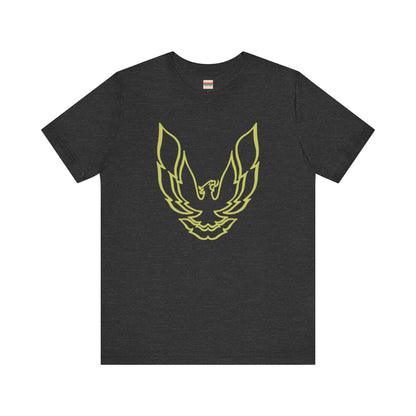 The Pontiac Trans Am Phoenix Shirt - Unisex Jersey Short Sleeve Tee by Printify is a classic black T-shirt that showcases a stylized yellow phoenix design on the front, reminiscent of the iconic Pontiac Trans Am. The shirt is displayed laid flat against a white background.