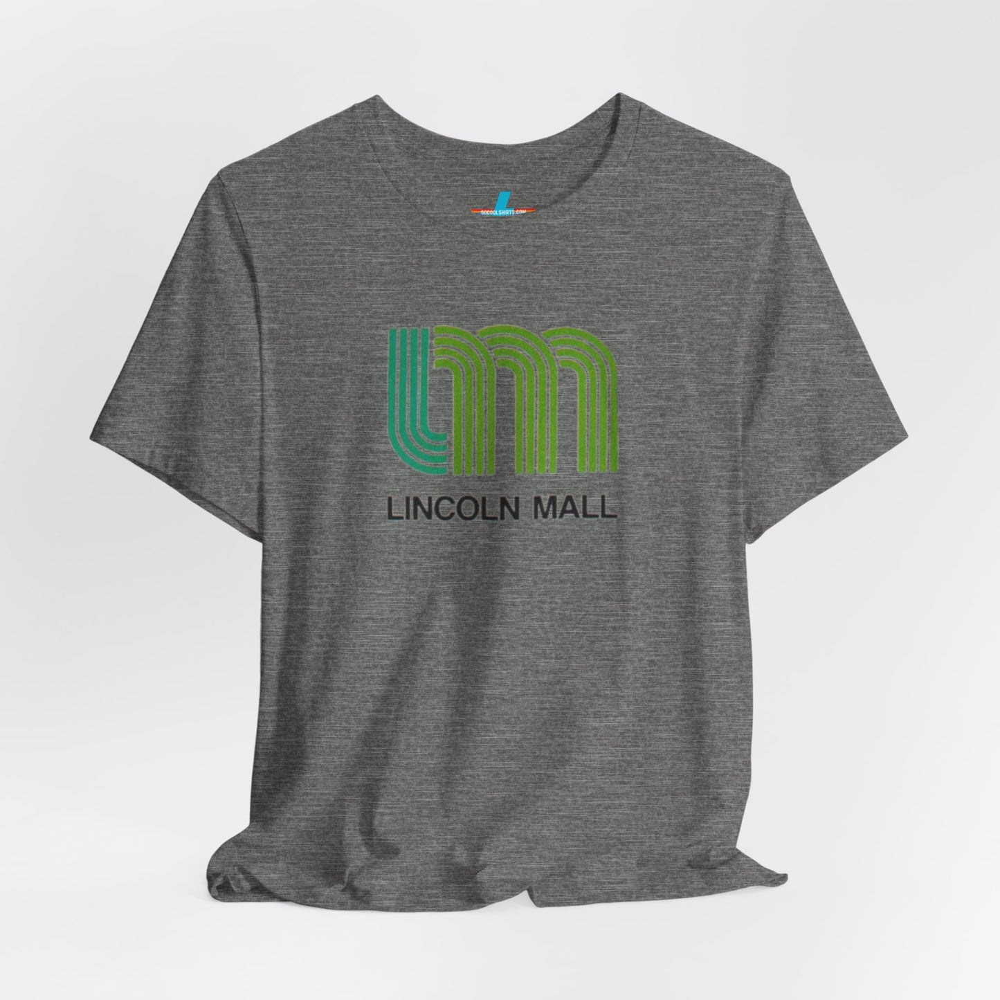 A light green unisex jersey short sleeve tee by Printify features "LINCOLN MALL" written under a retro-styled green and blue curved line design, celebrating the 70s and 80s shopping era in Lincoln Mall Matteson.