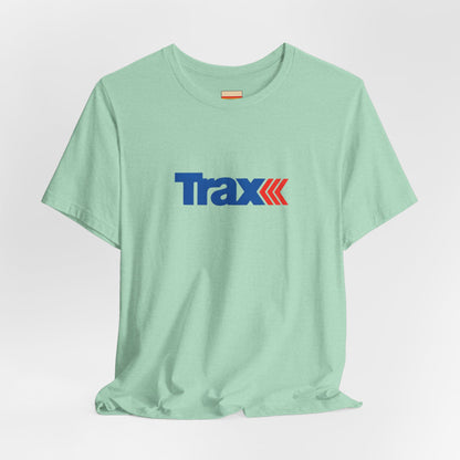 A gray unisex jersey short sleeve tee from Printify, inspired by retro 1980s Kmart style. The "Trax" logo is printed in blue letters, followed by three red arrows pointing to the right. This classic Trax Brand T-shirt is laid flat against a white background, capturing nostalgic fashion vibes.