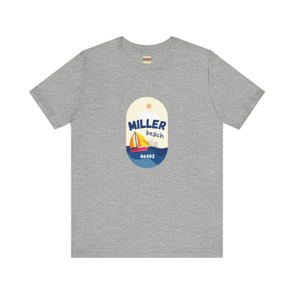 The Miller Beach Sailboat - Unisex Jersey Short Sleeve Tee by Printify features a vibrant graphic design portraying a sailboat on water with a sun above it and the text "MILLER beach 46403." This white retail fit shirt is crafted from soft Airlume combed cotton and showcases rounded graphics in blue, orange, and yellow.