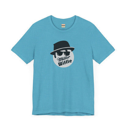 A purple unisex jersey tee from Printify, named the "Miller Wiffel Ball - Blues Brothers - Unisex Jersey Short Sleeve Tee," features a stylized graphic of a ball wearing a black fedora and sunglasses with the text "Miller Wiffel" below it. Another identical soft cotton t-shirt is neatly folded underneath, highlighting its breathable fabric.