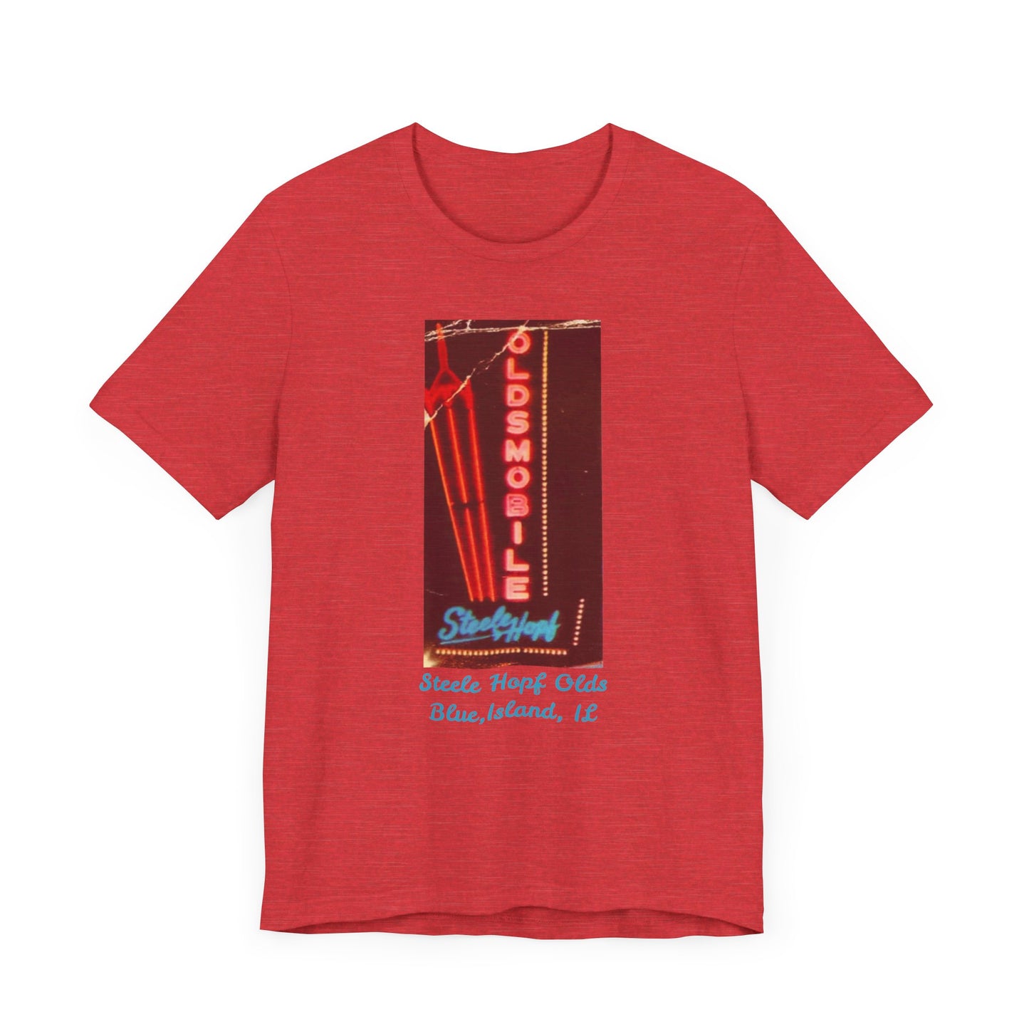 The Blue Island Illinois Steele-Hopf Oldsmobile Unisex Jersey Short Sleeve Tee by Printify features a vibrant red design with an image of a vintage neon sign. The sign displays "OLDSMOBILE" in vertical red letters and "Strafford" in blue cursive script. Below the sign, light blue text reads "Sleets Hopf Olds" and "Blue Island, IL," making it an ideal retro-inspired tee for classic car enthusiasts.