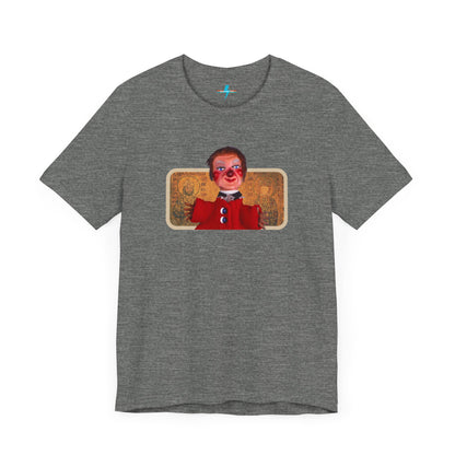 The rust-colored Printify Lady Elaine - Mr. Rogers Unisex Jersey Short Sleeve Tee features a detailed image of the Lady Elaine puppet, dressed in a red outfit with a painted face, set against an intricate artistic backdrop. The centrally positioned puppet and vivid colors create a striking contrast against the muted tone of the shirt, evoking nostalgic memories of Mr. Rogers' Neighborhood.