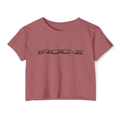 A grey, short-sleeve, rounded-neckline Women's Festival Crop Top by Printify, featuring "IROC-Z" printed in bold black letters across the chest. Perfect for any festival, this Chevrolet Iroc Z-inspired top from the 1980s stands out against a plain white background.