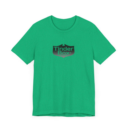 A light blue Printify "The Tinder Box 1980s" unisex jersey short sleeve tee featuring the "Tinder Box" logo in the center. The logo consists of a dark shield with the words "Tinder Box" in white text, with a small flame icon replacing the dot above the "i".
