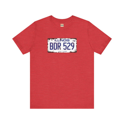 The Printify Blues Brothers BDR 529 License Plate Unisex Jersey Short Sleeve Tee showcases a vintage Illinois license plate graphic with "BDR 529" prominently displayed, as famously seen in the Blues Brothers film. The design includes "Illinois" and "Land of Lincoln" above and below the numbers, with a weathered, rustic look that enhances its retro appeal.