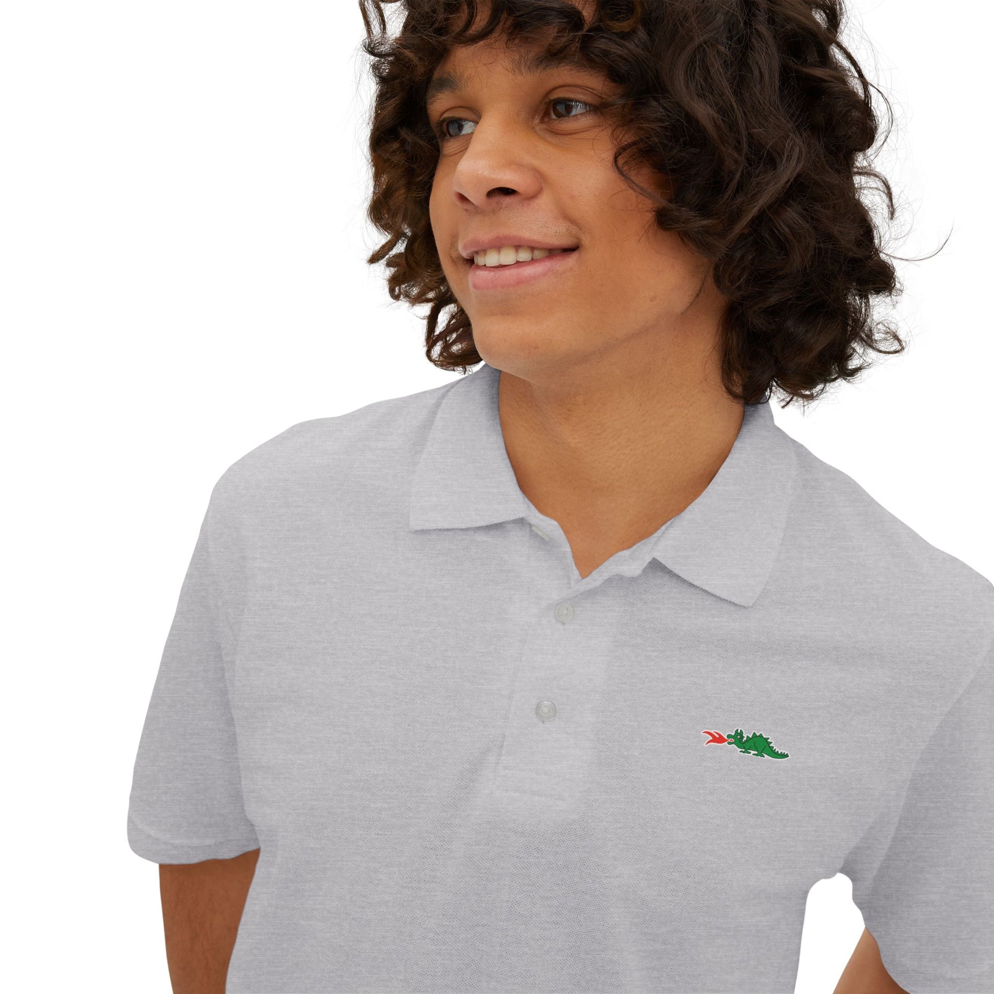 A person with curly hair wearing a navy blue Printify Braggin' Dragon - 1980s Sears Men's Piqué Polo, featuring a small embroidered dragon logo on the left chest, smiles against a plain white background.