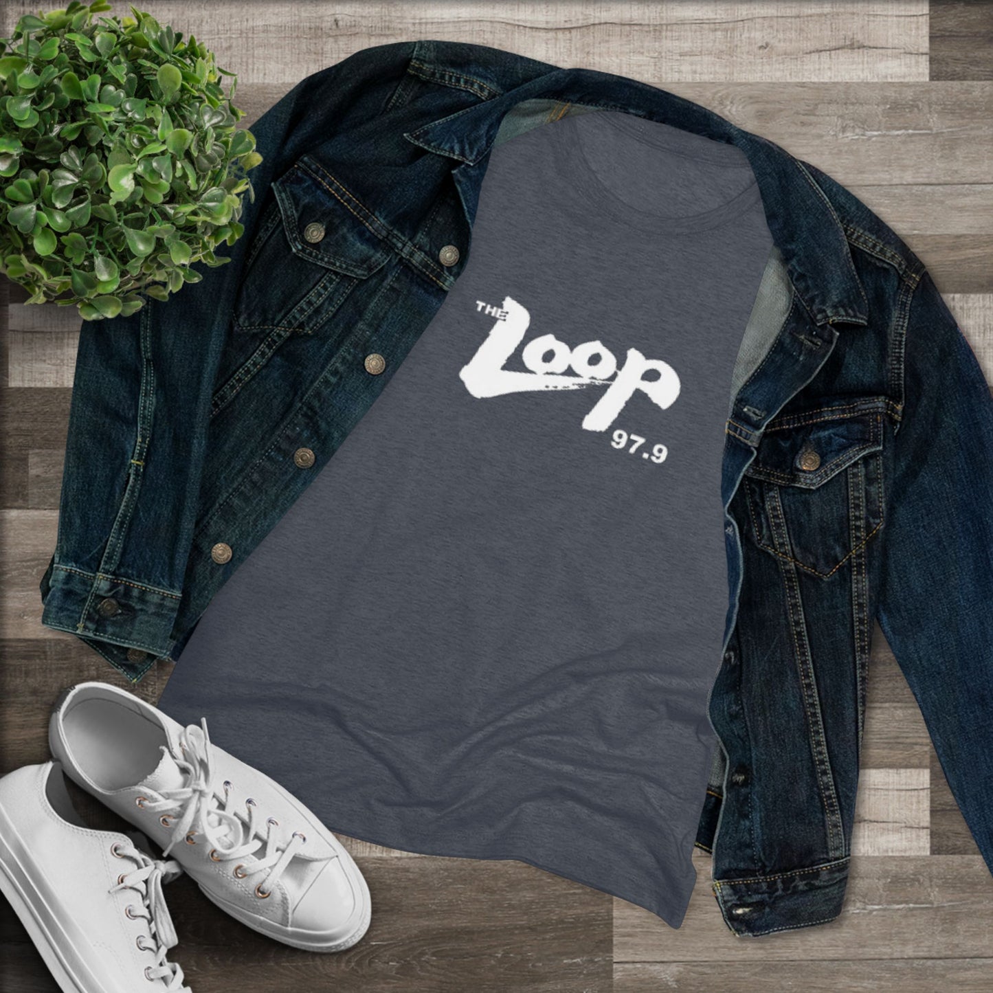 A dark gray, premium tri-blend fabric t-shirt with "The Loop - Chicago Radio 97.9" printed in white text across the chest. The casual, slightly distressed style of the text gives it a vintage look. The classic rock t-shirt is laid flat against a white background. This women's triblend tee by Printify offers a stylish homage to vintage radio days.