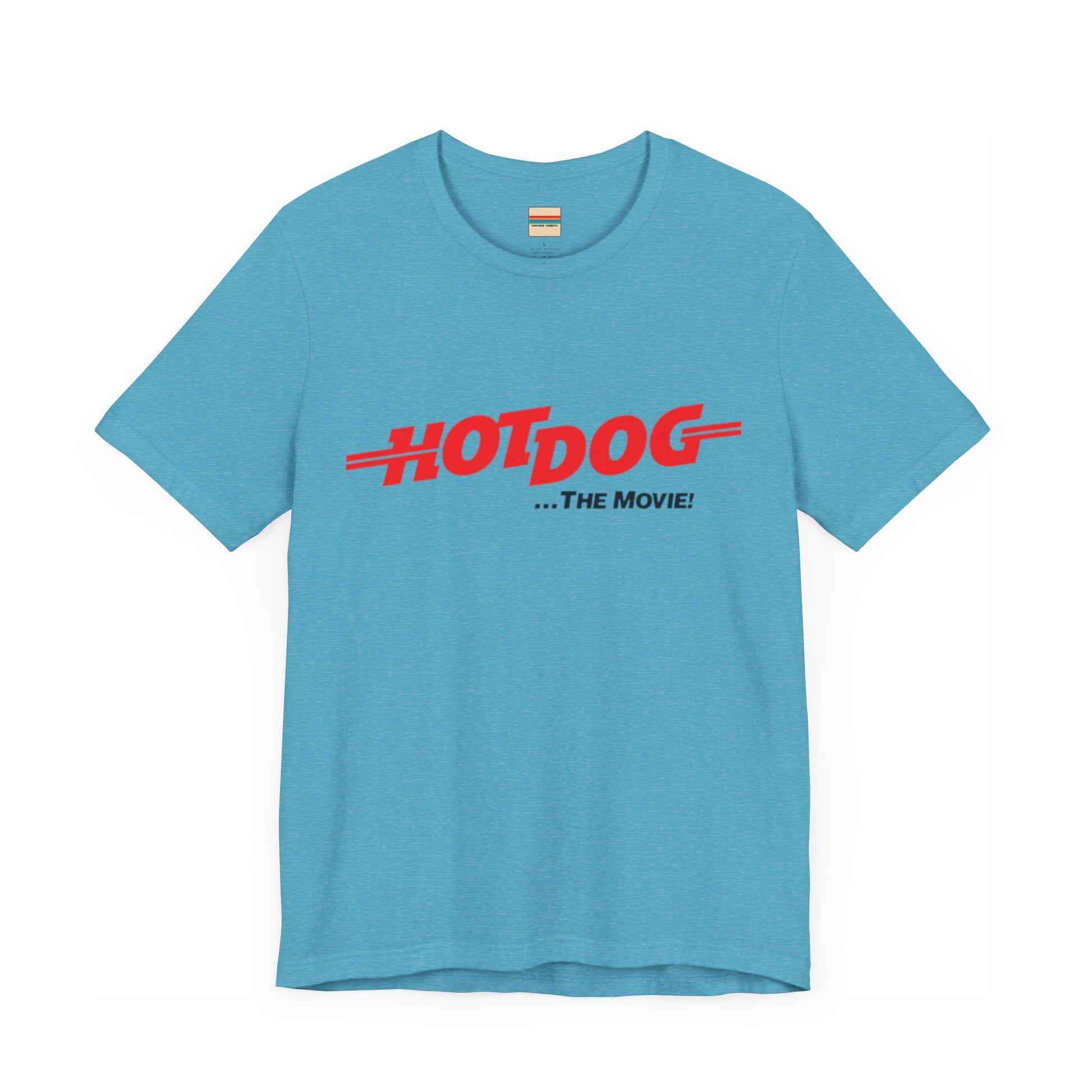 A smiling man and woman interact while wearing matching yellow "Hot Dog The Movie 1984 - Unisex Jersey Short Sleeve Tee" by Printify, featuring bold red "HOT DOG THE MOVIE" text. Their vibrant tees perfectly complement their blue jeans, with the man casually having his hands in his pockets and the woman resting one hand on his shoulder.