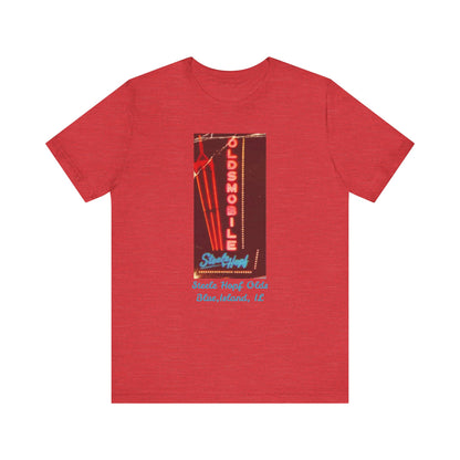 The Blue Island Illinois Steele-Hopf Oldsmobile Unisex Jersey Short Sleeve Tee by Printify features a vibrant red design with an image of a vintage neon sign. The sign displays "OLDSMOBILE" in vertical red letters and "Strafford" in blue cursive script. Below the sign, light blue text reads "Sleets Hopf Olds" and "Blue Island, IL," making it an ideal retro-inspired tee for classic car enthusiasts.