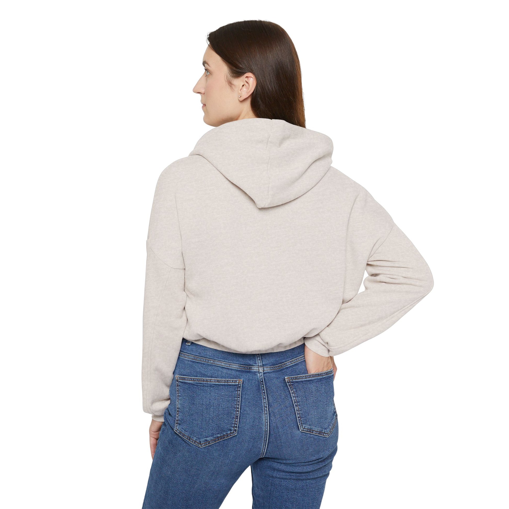 A person confidently stands in front of the camera with one hand on their hip, wearing a Printify "Say Perhaps to Drugs" Women's Cinched Bottom Hoodie. Crafted from soft Airlume cotton, this light-colored cropped hoodie pairs stylishly with blue jeans.