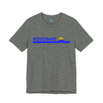 The Fotomat 1970s Retro T-Shirt by Printify is a dark gray short-sleeve shirt that features the word "FOTOMAT" in bold blue capital letters and a blue and yellow graphic design resembling layered lines and an upside-down triangle. This Tshirt captures the essence of 80s nostalgia with its centered, retro design.