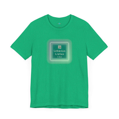 Introducing "The Lebanon Loop - Indiana" unisex jersey short sleeve tee by Printify. This green t-shirt features a graphic of a road sign displaying "39 Lebanon Lizton 1 MILE" within a slightly glowing square frame. It's crafted from 100% Airlume cotton and photographed flat on a white background.