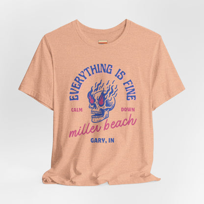 The Miller Beach Calm Down Everything is Fine - Unisex Jersey Short Sleeve Tee from Printify, crafted from soft Airlume combed cotton, showcases a peach-colored design with a flaming skull in the center. Above the design, it reads "Everything is fine," and below it says, "Calm down Miller Beach." In smaller text at the bottom, it reads "Gary, IN.