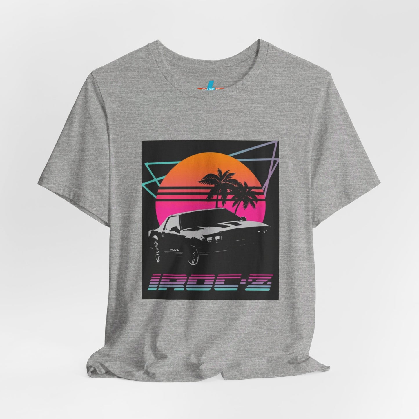 A Chevrolet Camaro iRoc Z Z28 T-Shirt 1980's by Printify, featuring a retro design with a black car, palm trees, and a sun setting in the background. The design includes geometric lines in neon colors and the text "IROC-Z" at the bottom, perfect for fans of the 1980s Chevy Camaro.