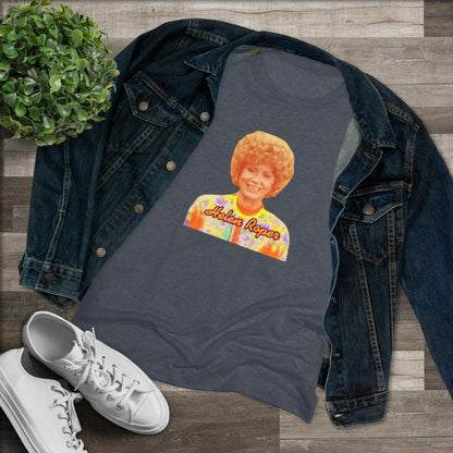 A Women's Triblend Tee by Printify, titled "Helen Roper - Three's Company," features a red design with an illustration of a smiling person with curly hair and colorful clothing. Below the illustration, the text "Helen Roper" is written in a bold, retro font, capturing the essence of vintage TV humor.