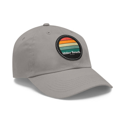 The Miller Beach Retro Sunset - Dad Hat with Leather Patch (Round) by Printify is a pink baseball cap crafted from bio-washed chino twill for added comfort. It features a PU leather patch adorned with horizontal stripes in red, orange, yellow, green, and blue. Below the stripes, "Miller Beach" is embroidered in white. An adjustable strap at the back ensures a perfect fit.