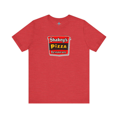 A black Shakey's Pizza - 1980s Retro Logo - Unisex T-Shirt by Printify hangs against a white background. The shirt features a colorful graphic with the text "Shakey's Pizza Restaurant" in white, yellow, and black lettering on a red background, resembling vintage pizza joints signage. This retro tee brings nostalgic vibes of classic pizzerias.