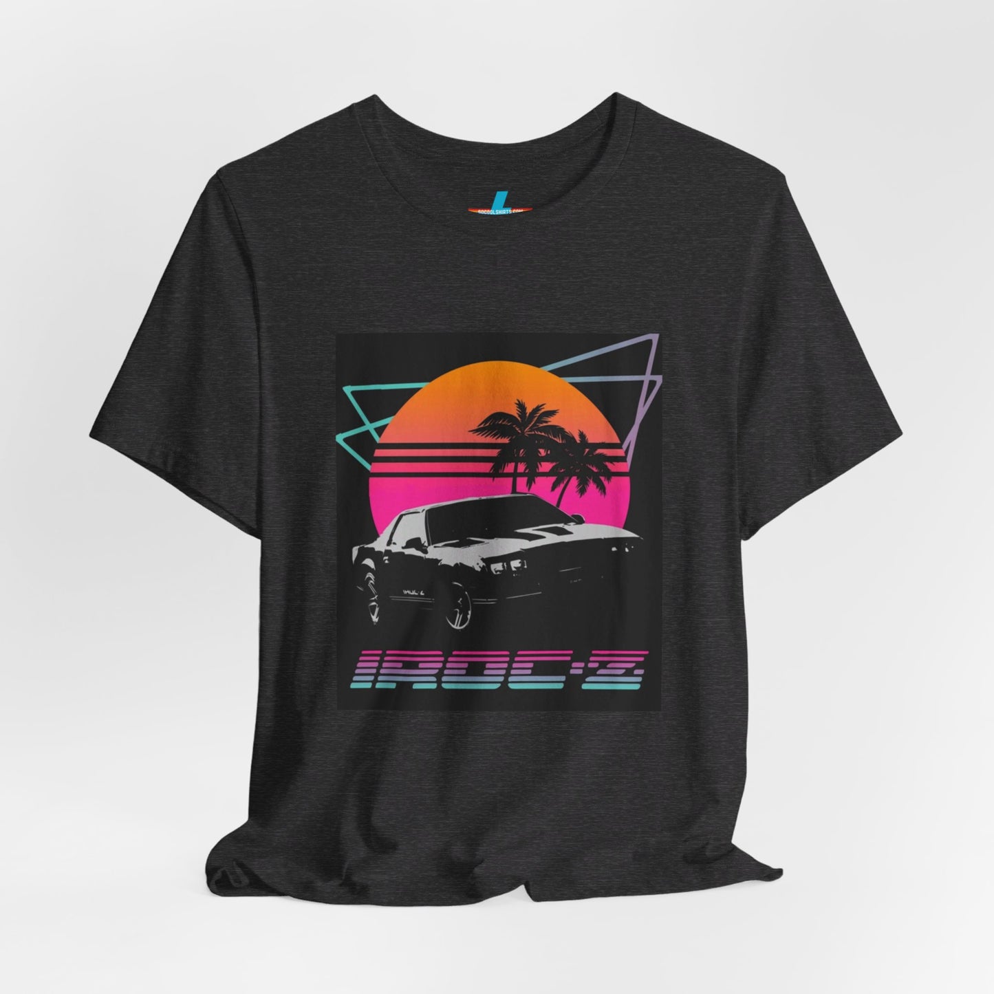 A Chevrolet Camaro iRoc Z Z28 T-Shirt 1980's by Printify, featuring a retro design with a black car, palm trees, and a sun setting in the background. The design includes geometric lines in neon colors and the text "IROC-Z" at the bottom, perfect for fans of the 1980s Chevy Camaro.