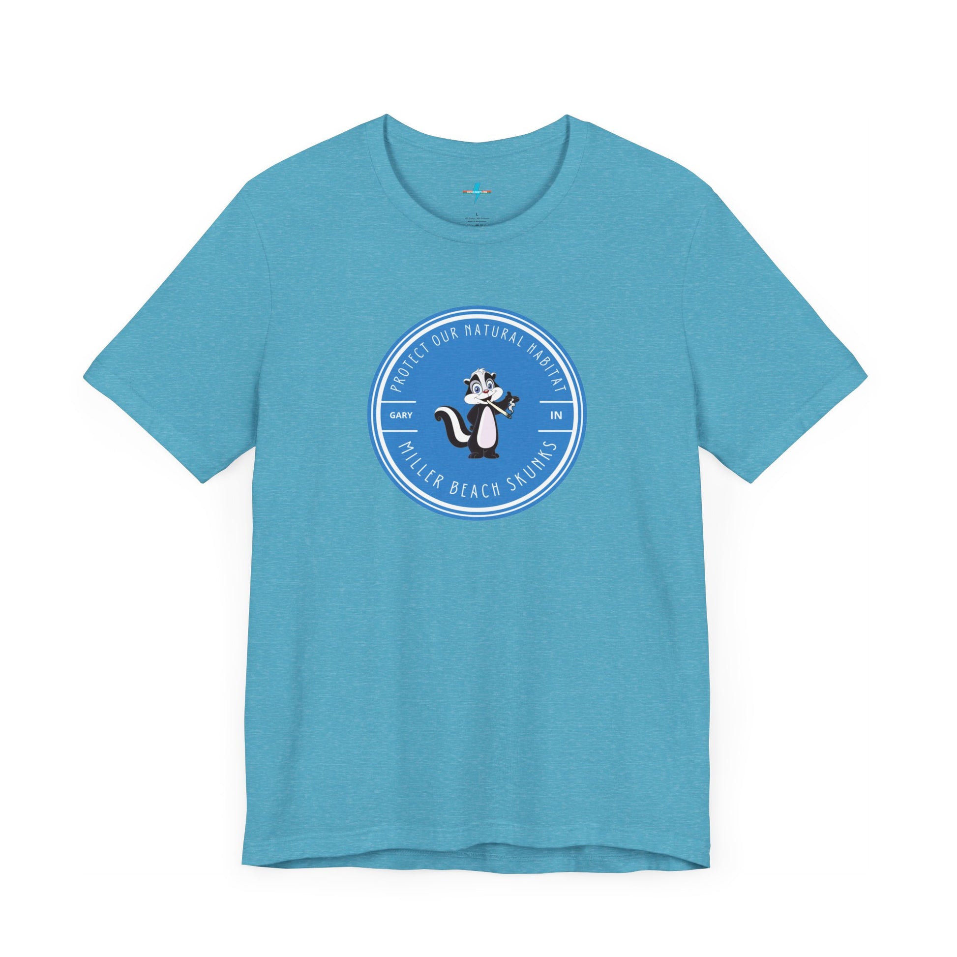 The Printify Miller Beach Skunks - Unisex Jersey Short Sleeve Tee is a gray T-shirt that features a circular blue logo at the center. Inside the logo, there is an illustration of a skunk with the text "Protect Our Habitat" and "Miller Beach Skunks" around the border, promoting environmental consciousness. The upper left part of the logo reads "Gary, IN.